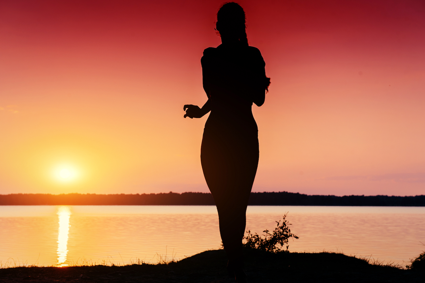 silhouette of fit running girl outdoors against a red sunset; benefits of full body red light therapy for health and wellness