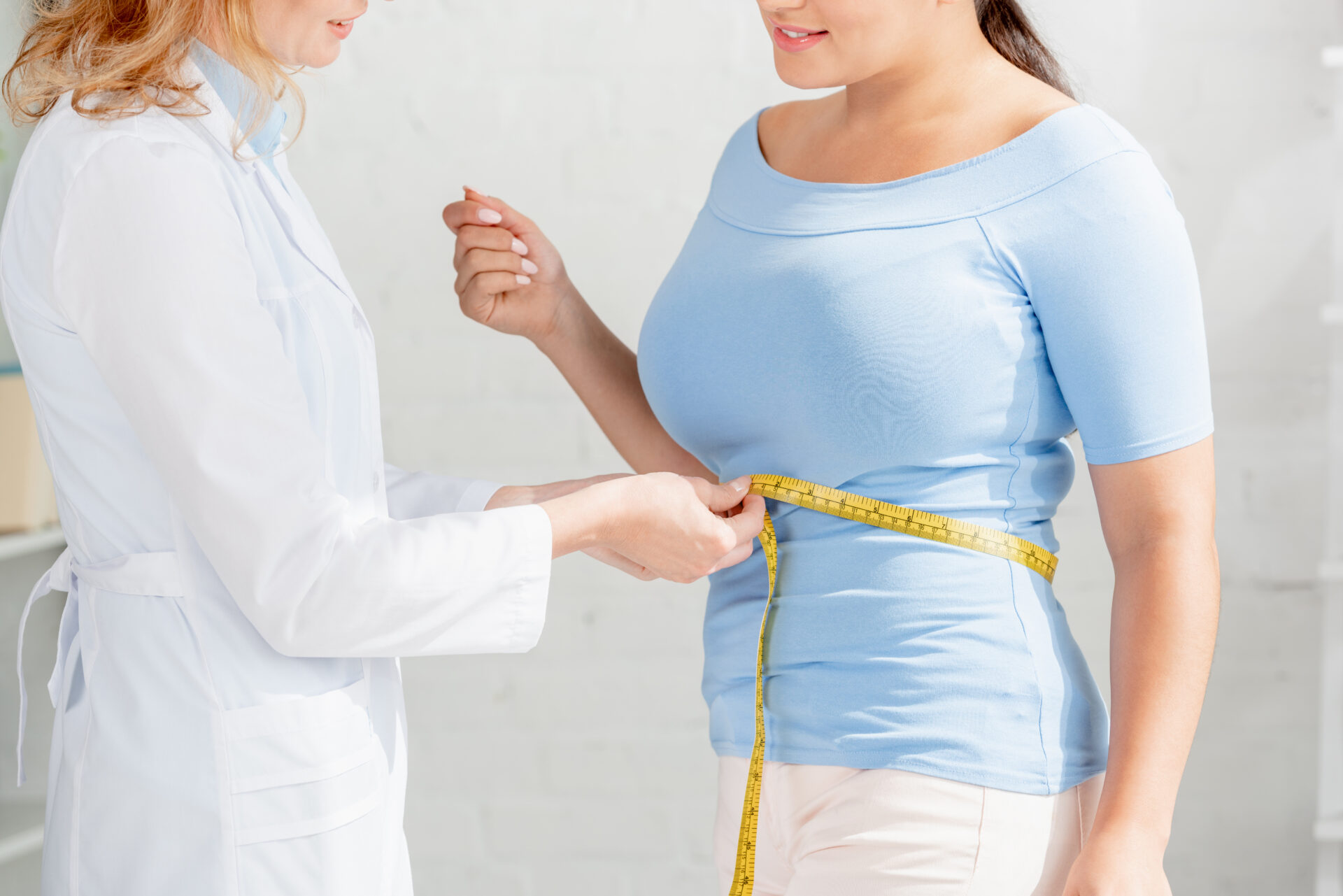 weight loss doctor measuring a patient’s waist, possible provider of red light therapy for weight loss